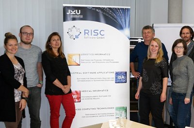 7 Personen stehend neben Roll-up der RISC Software GmbH