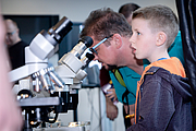 Junge sitzt bei Mikroskop und macht große Augen